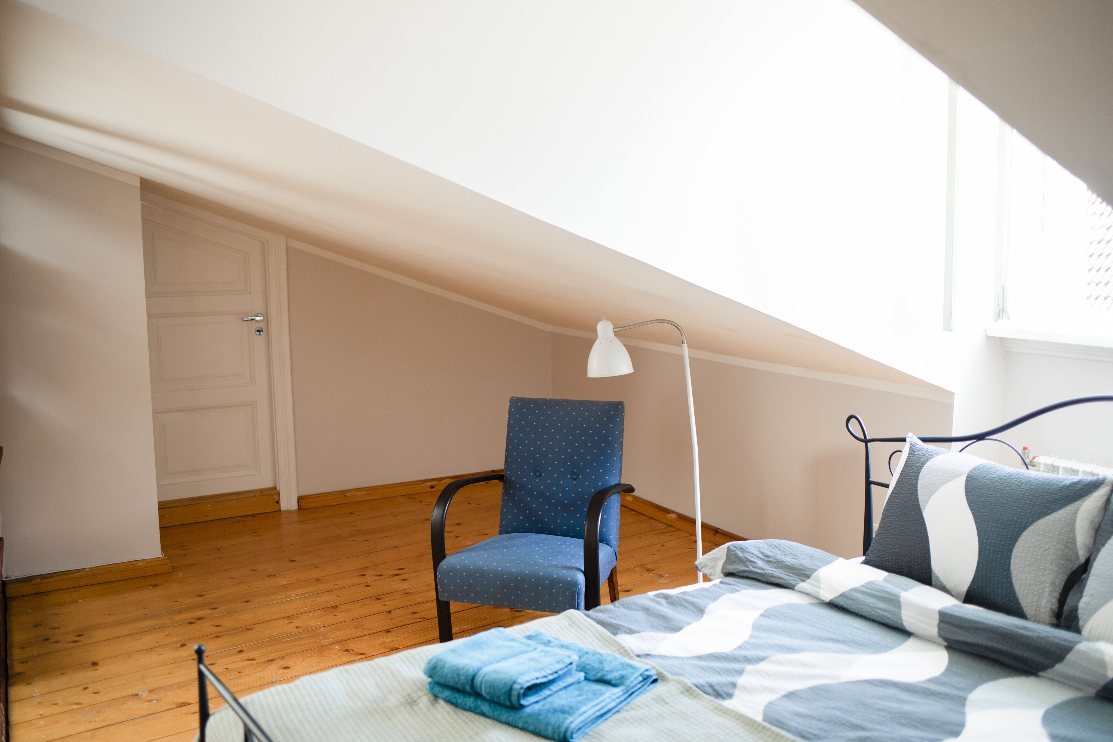 Une chambre à coucher avec un lit, une chaise, une lampe et une porte.