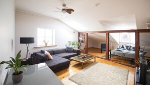 Un salón amplio con un sofá gris oscuro, una mesa de centro y un ventanal grande.