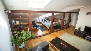 Una habitación estilo loft con tragaluces, vigas de madera, una cama, un escritorio y un televisor.
