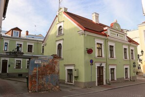 Un edificio histórico con fachada verde, detalles blancos y tejado de tejas rojas.
