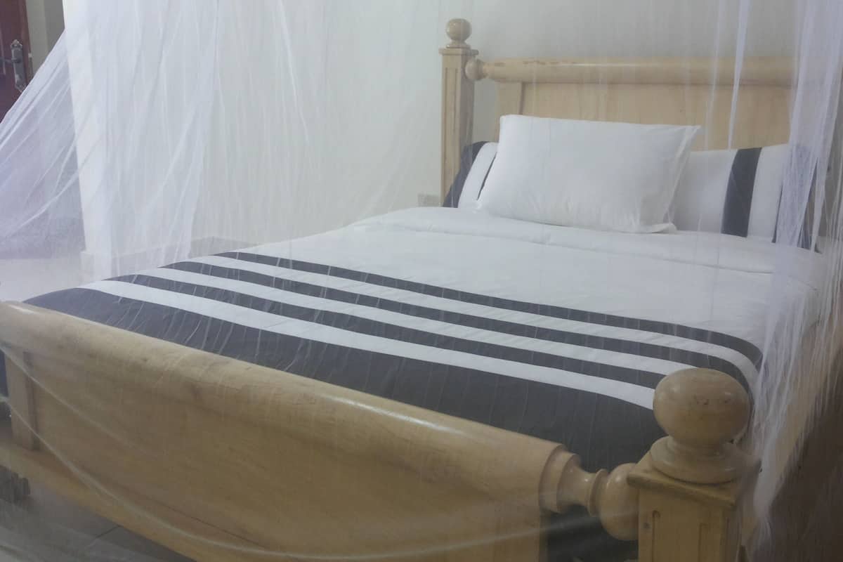A bed with a wooden headboard, white bedding, and a striped blanket.