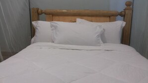 A bed with a wooden headboard and white bedding. - Skypa Hotel (Yumbe)