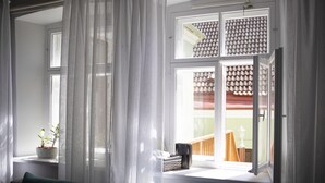 Una habitación con ventana, sofá verde, planta en maceta y radiador.