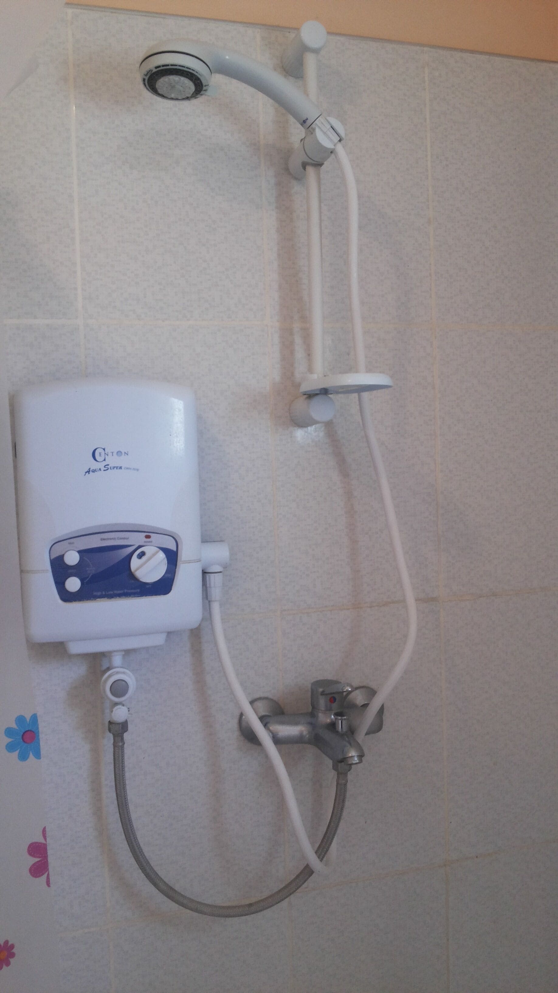 A wall-mounted shower unit with a control panel, a handheld showerhead, and a handheld faucet.