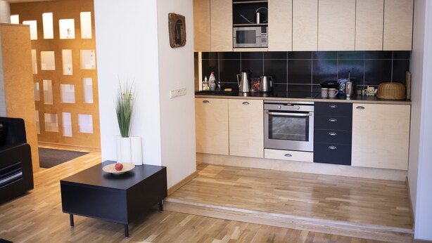 A modern kitchen with wooden cabinets, a built-in oven, and a black countertop. - City heart Kvartal-Tartu Home Apartments (Tartu)