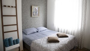 A bedroom with a bed, a ladder, a framed picture on the wall, and a window with curtains. - City heart Kvartal-Tartu Home Apartments (Tartu)