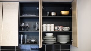 A kitchen with open cabinets displaying various dishes, glasses, and cookware. - City heart Kvartal-Tartu Home Apartments (Tartu)