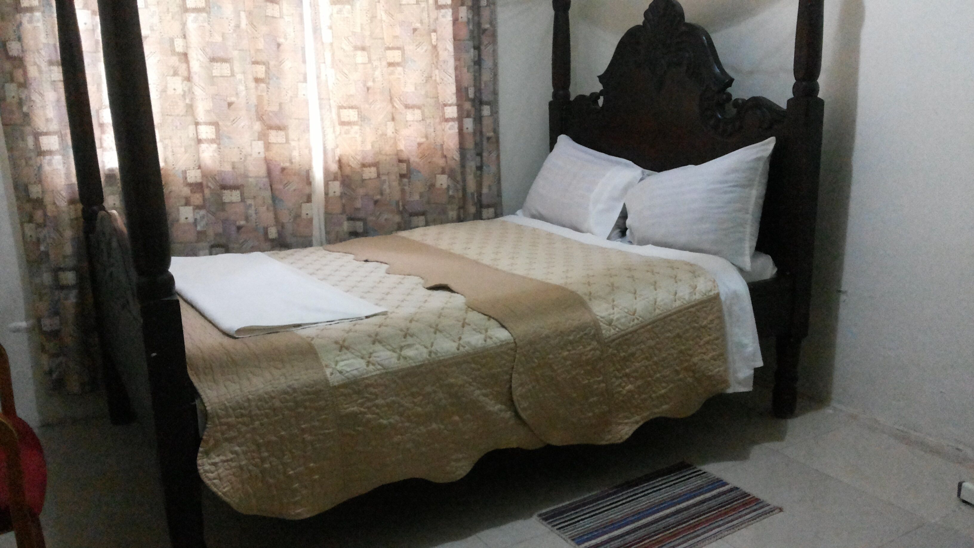 Una cama con cabecera, colcha y almohadas.