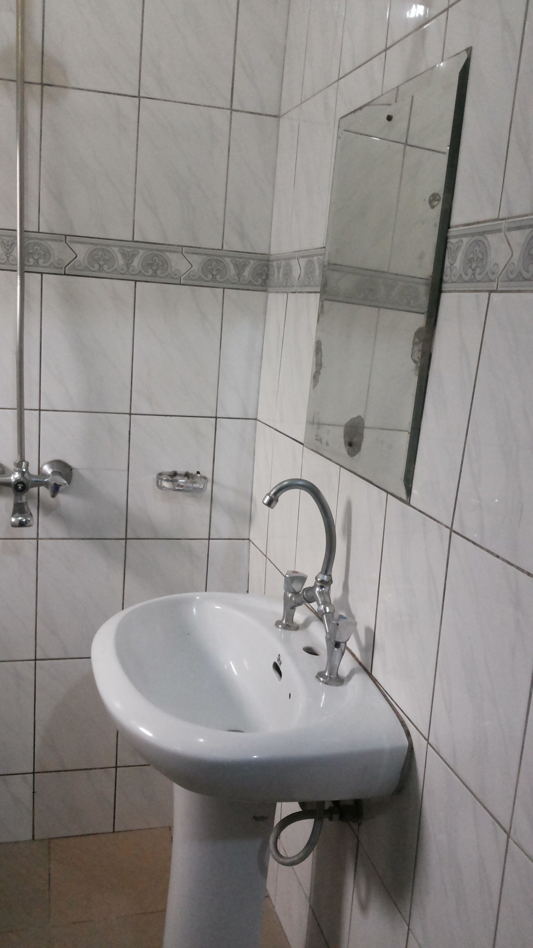 A bathroom with a white sink, a mirror, and tiled walls.