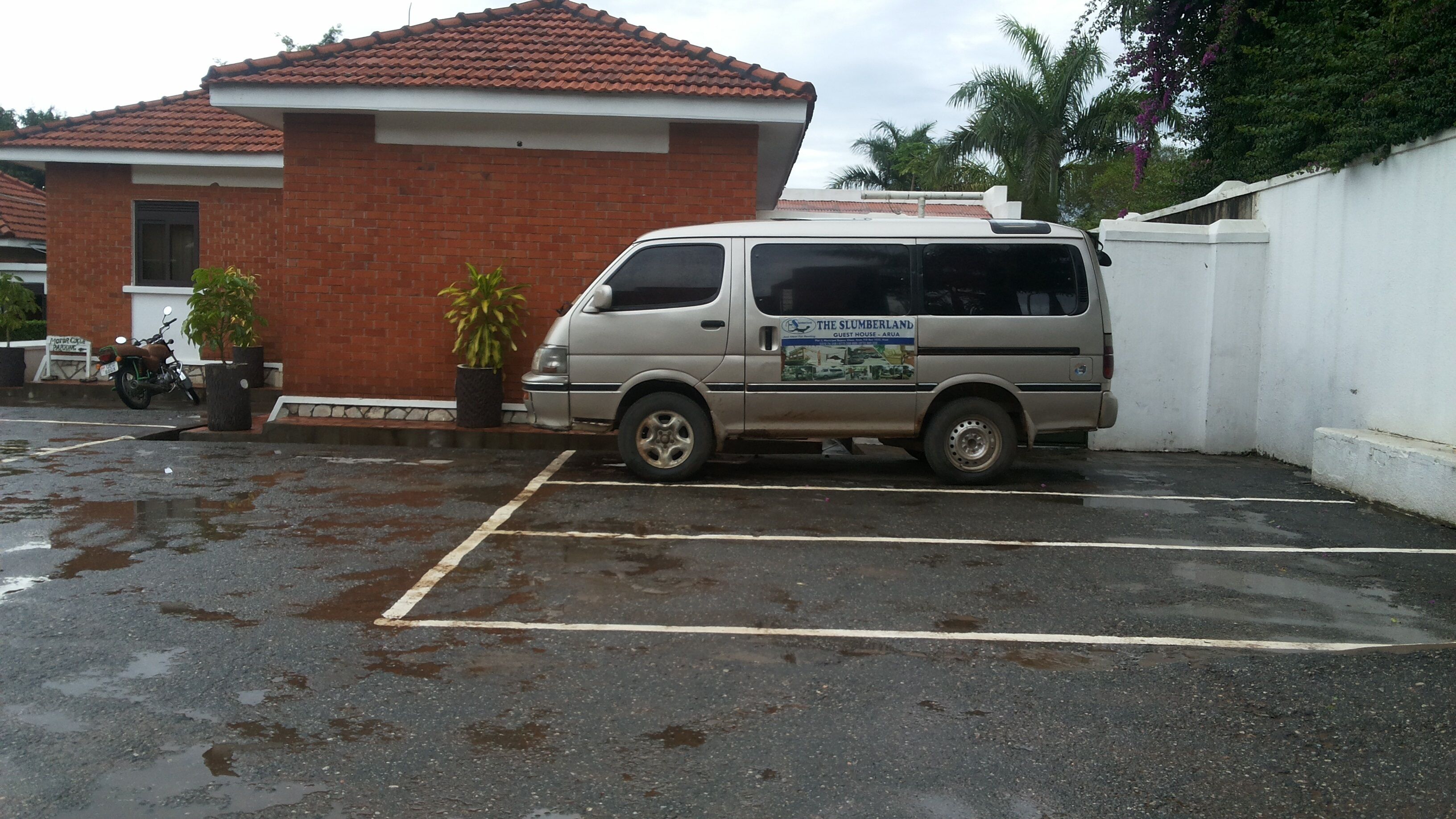 Una camioneta estacionada en un estacionamiento mojado con un edificio de ladrillo al fondo.