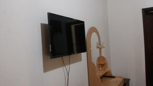 Un televisor montado en la pared con una silla de madera al frente.
