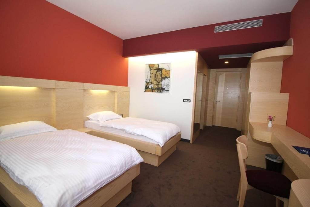 A hotel room with two beds, a desk, and a chair.