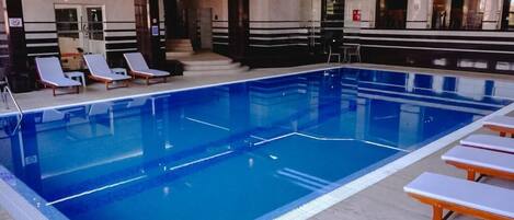 Una piscina interior con sillones de descanso y una escalera que conduce a un nivel superior.