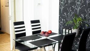 Uma sala de jantar com mesa de vidro, cadeiras listradas em preto e branco, e uma tigela de maçãs.