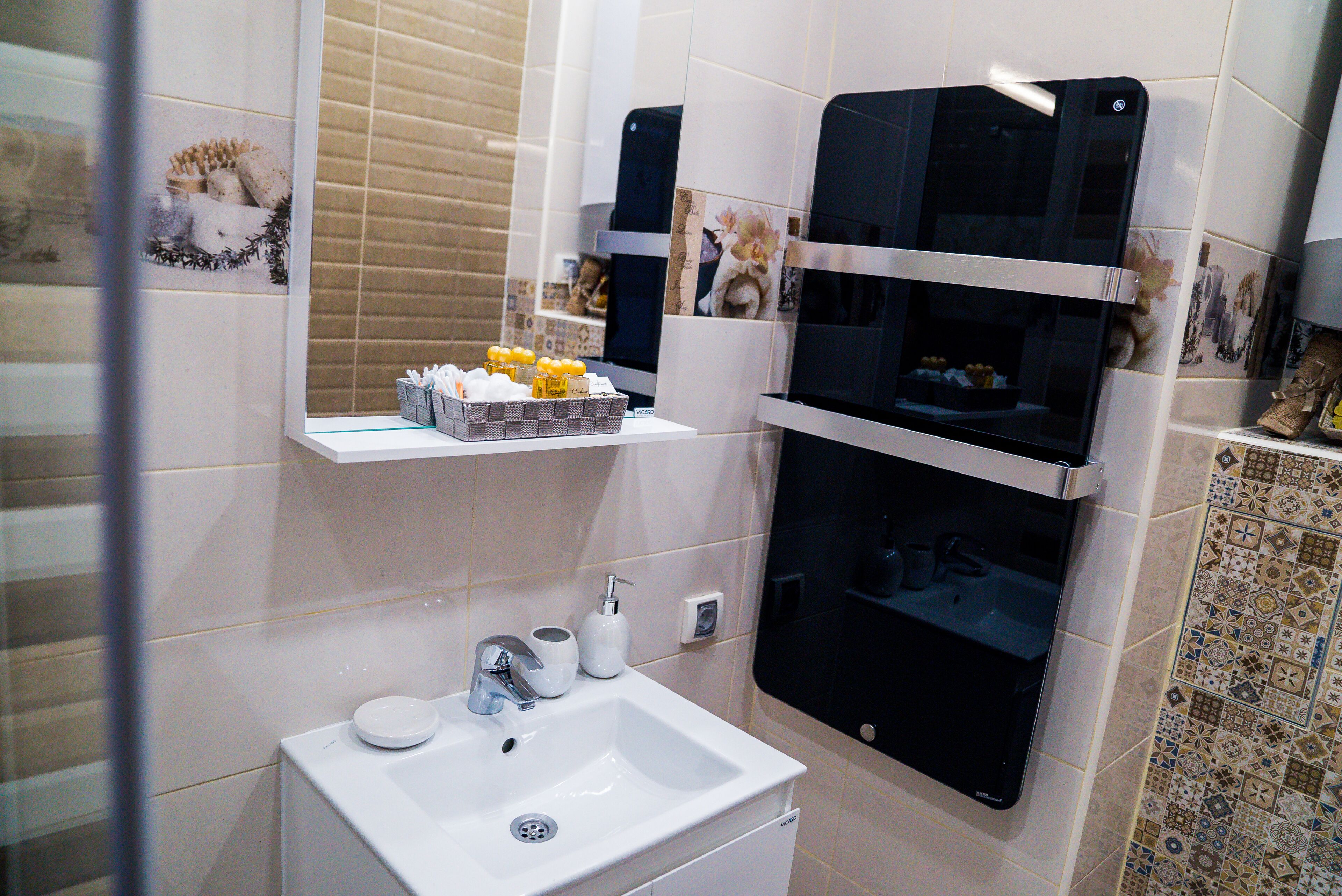Un baño con lavamanos blanco, un espejo y repisas con artículos de aseo.