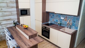 Une cuisine moderne dotée de plans de travail en bois, d’un four encastré, d’un four à micro-ondes et d’un évier agrémenté d’un pare-éclaboussures décoratif.