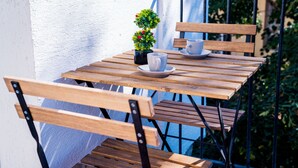Une table en bois, avec deux tasses et soucoupes blanches, une petite plante en pot et un banc.
