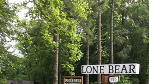 Een bord met 'Lone Bear Cottages' en een huis in een bebost gebied.