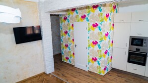 Eine Küche mit Holzboden, einer weißen Tür und einer farbenfrohen abstrakten Wand.