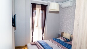 Ein Schlafzimmer mit Bett, Vorhängen, einer Pendelleuchte und einer Wand-Klimaanlage.