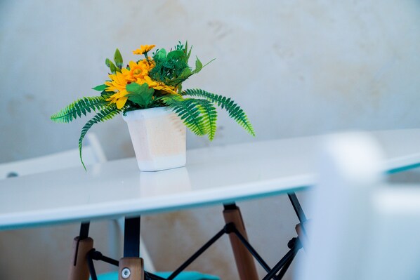 A potted plant with yellow flowers on a white table against a plain wall. - Sofia Central Pretty Apartment (Sofia)