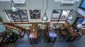 Un restaurante con mesas y sillas de madera, lámparas colgantes y un expendedor.
