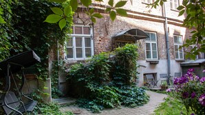 A courtyard with a brick building, a covered seating area, and a pathway.