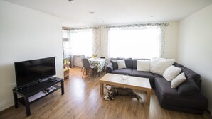 A living room with a TV, sofa, coffee table, and a dog lying on the floor. - Tiigi Bibliotheca- Tartu Home Apartments (Tartu)