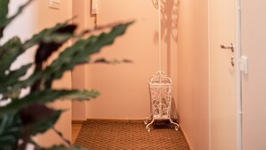 A narrow hallway with a patterned carpet, a white door, a coat rack, and a light fixture on the ceiling. - Tiigi Bibliotheca- Tartu Home Apartments (Tartu)