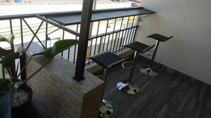 A balcony with a view of the street, a potted plant, and two bar stools. - Hotel Libano (San Francisco de Macorís)