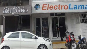A hotel named Hotel Libano with a modern facade, a white car parked in front, and a motorcycle parked outside. - Hotel Libano (San Francisco de Macorís)