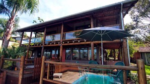 A wooden cabin with a pool, outdoor seating, and a covered patio. - Pousada Paraíso do Luz (Imbituba)