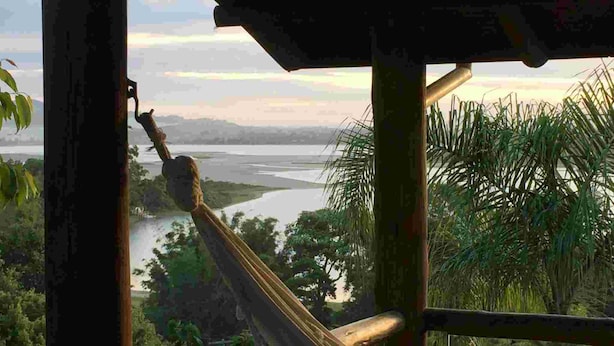 A hammock overlooking a river and greenery. - Pousada Paraíso do Luz (Imbituba)