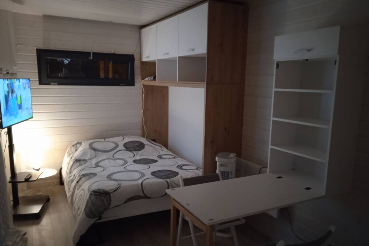 Ein Schlafzimmer mit Bett, Fernseher, Schreibtisch und Einbauschränken.