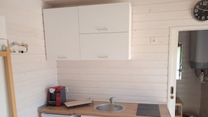 Eine kleine Küche mit Spüle, Kaffeemaschine und kleinem Kühlschrank.