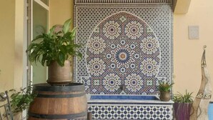 Un interior marroquí tradicional amb un paviment de rajoles, una paret decorativa i un llum de llanternes penjant.