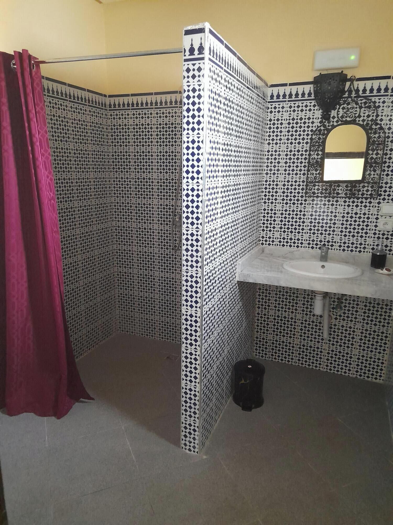 A bathroom with a corner shower, a sink, and a mirror.