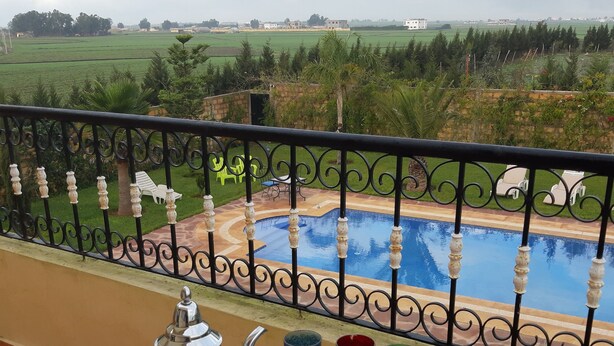 Un balcó amb vista a una piscina i camps verds.