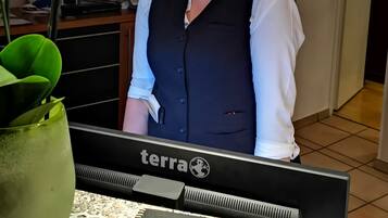 Mostrador de recepción con el logotipo de Terra, una orquídea blanca y un cartel de prohibido fumar.