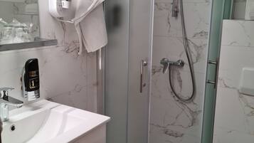Un baño moderno con ducha acristalada, lavabo blanco y retrete.