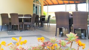 Un patio al aire libre con mobiliario de mimbre y una zona cubierta.