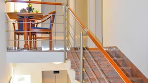 Un interior de varios niveles con escalera, zona de comedor y ascensor.