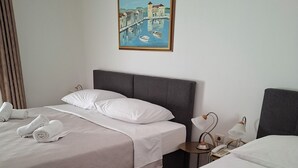 Habitación de hotel con dos camas, un cuadro de un puente, un teléfono y una lámpara en la mesita de noche.