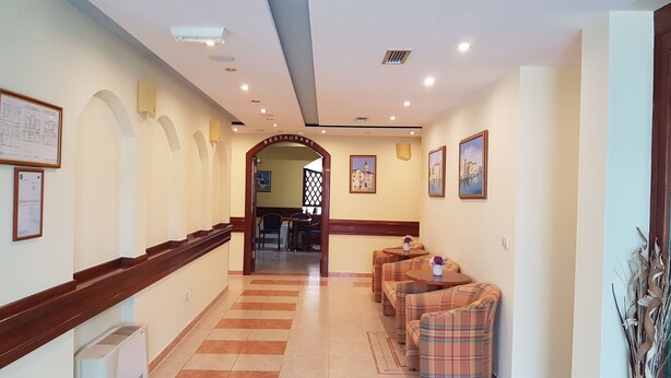 Un vestíbulo de hotel con piso a cuadros, una recepción y un área de descanso con sillones escoceses.