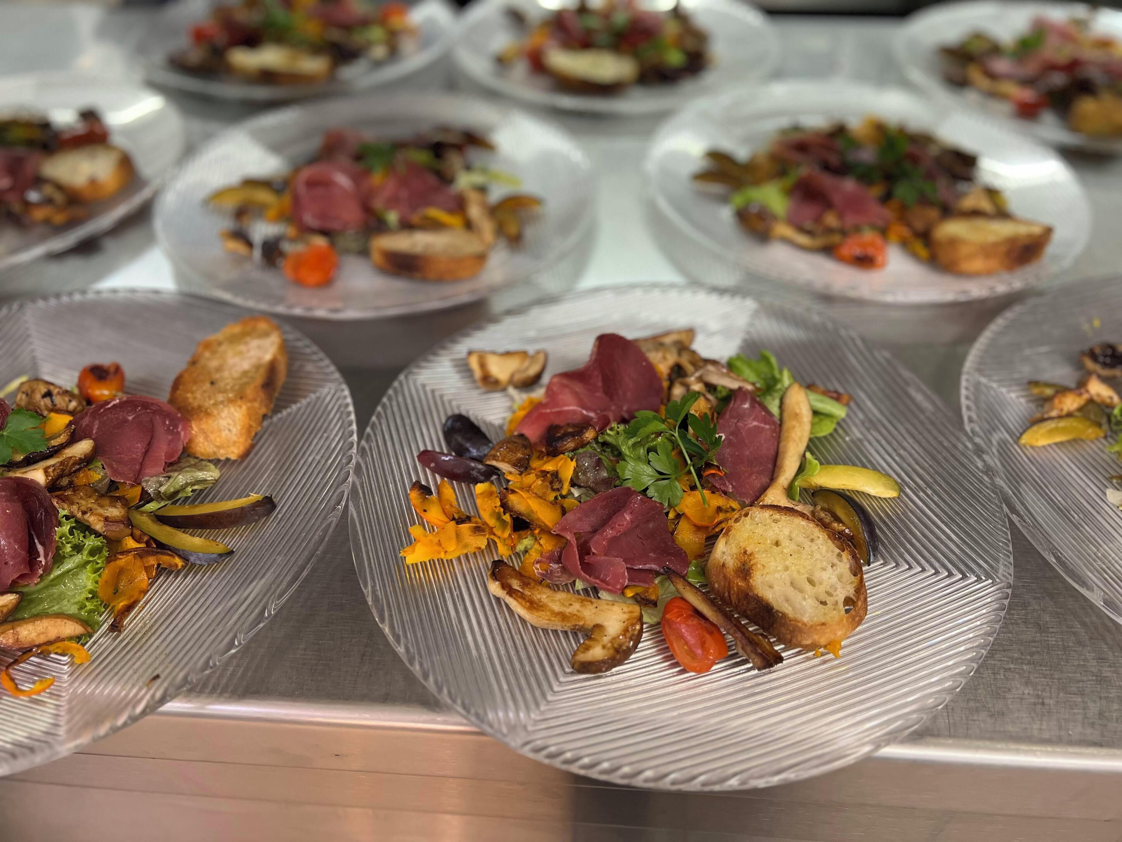 A buffet with various plated dishes, including salads, meats, and vegetables.