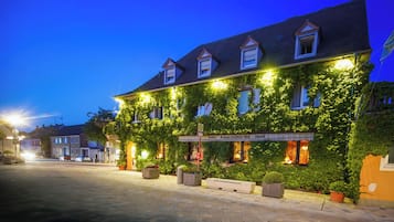 A hotel with ivy-covered walls, a signboard, and outdoor seating.