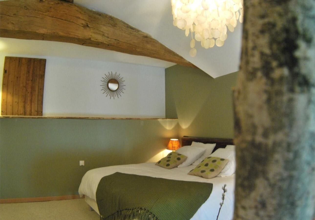 Un dormitorio con cama, una mesita de noche, un espejo montado en la pared y una lámpara colgante.