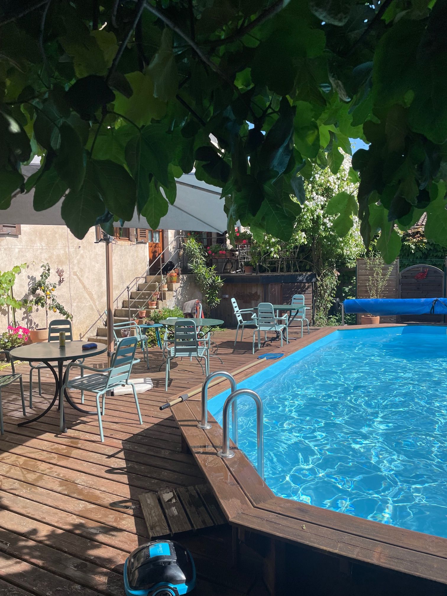 A swimming pool with a wooden deck, lounge chairs, and a table.