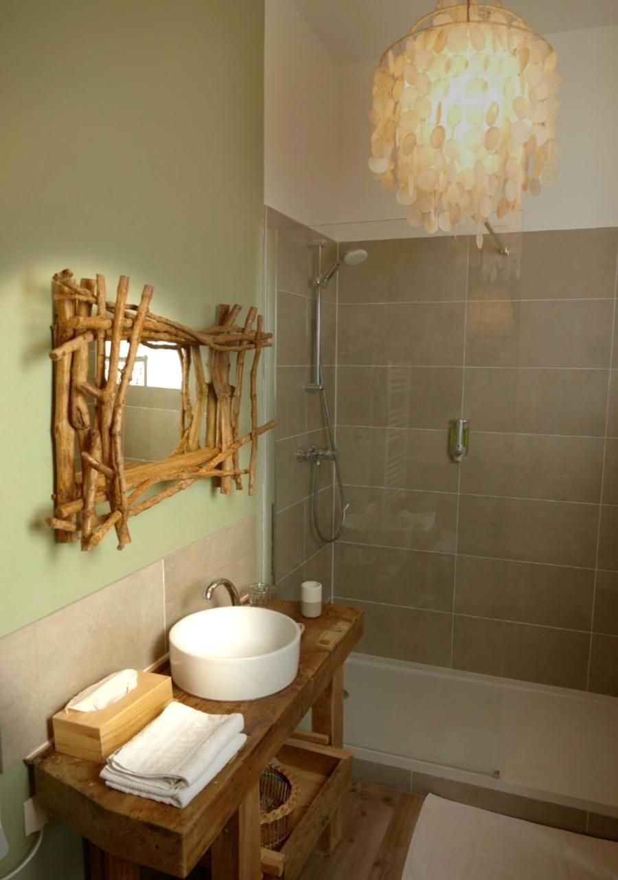 Un baño con tocador de madera, un lavabo redondo, un espejo y una ducha.