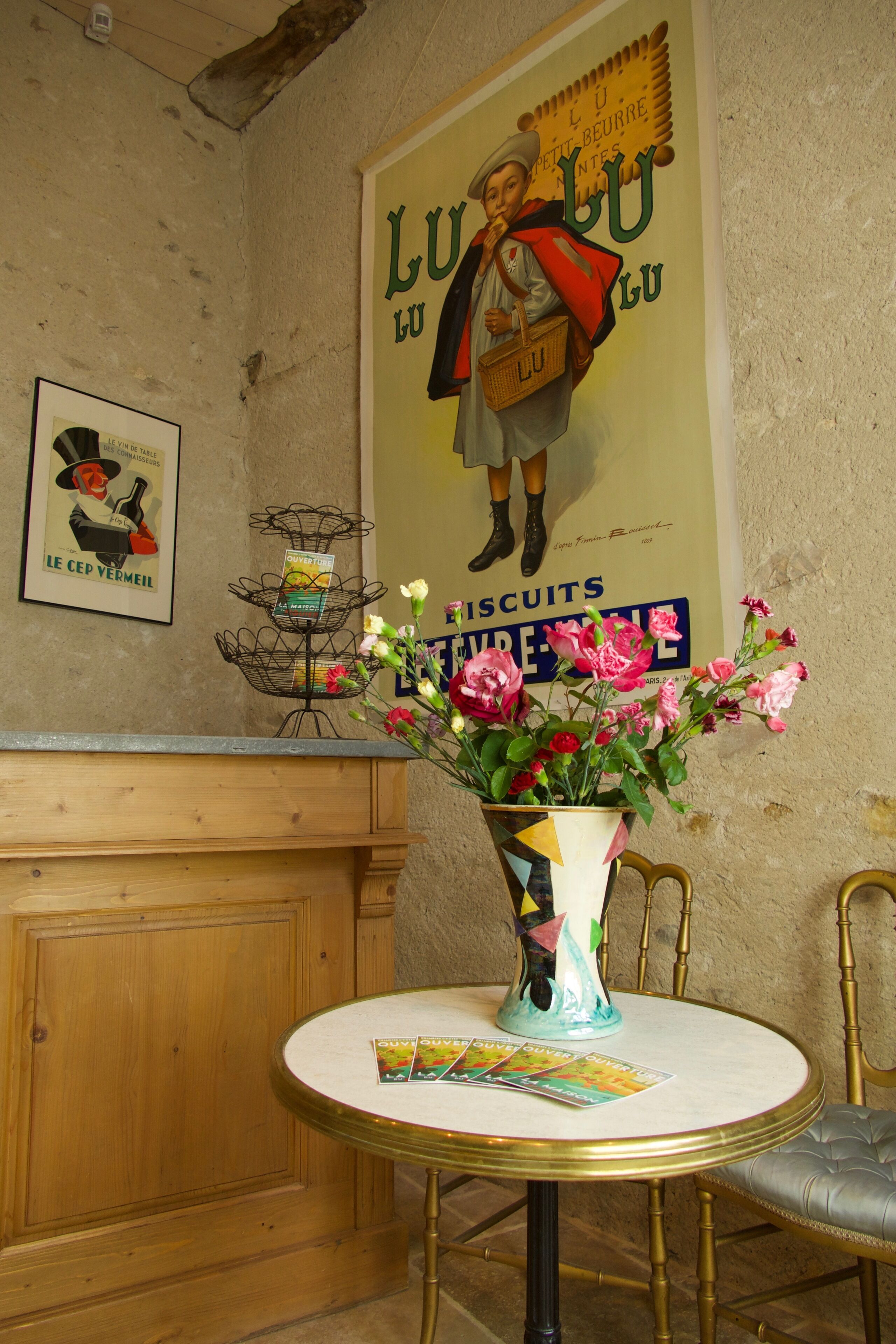 A round table with a vase of flowers, a magazine, and a poster on the wall.